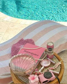 a wicker basket filled with personal items next to a swimming pool and beach towel