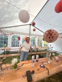 a man standing next to a wooden table covered in paper lanterns and other items on it