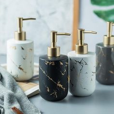 three black and white soap dispensers sitting on a table next to a book