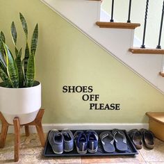 there is a plant and shoes on the floor in front of a sign that says shoes off please