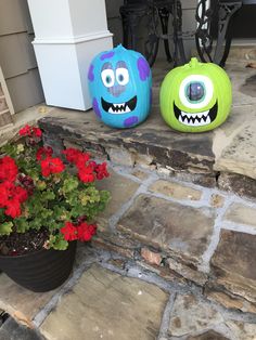 two decorated pumpkins sitting on top of a stone porch