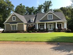 a large house sitting in the middle of a lush green field next to a road