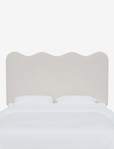 a bed with a white headboard and pillows