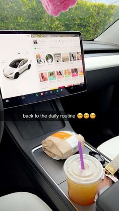 a laptop computer sitting on top of a car dashboard next to a cup of coffee