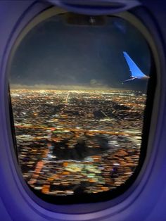 an airplane window looking out at the city lights and buildings from inside it's plane