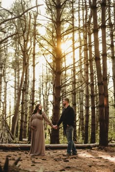 a pregnant couple holding hands in the woods