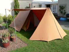 an orange tent sitting on top of a lush green field next to a brick building