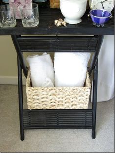 a black table with two baskets on it and white towels in the bottom basket next to it