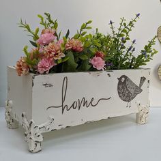 a wooden box with flowers in it sitting on a table next to some clocks and other decorations