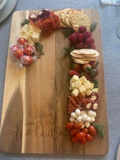 a wooden cutting board topped with different types of cheese and crackers on top of a table