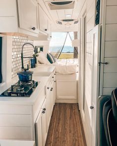 the interior of a small camper with wood flooring and white cabinets on both sides