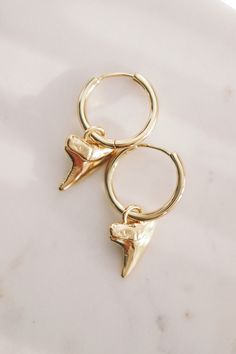 Often represented as symbols of strength, courage, and protection, shark teeth can be powerful amulets of individual expression. These shark tooth hoop earrings summon visions of prestige, strength, and good fortune. Wear them proudly and invoke your power. ✦ Available in both Sterling Silver and Gold Plated Brass ✦ ✦ DETAILS ✦✧ Mano (mah NO) - shark.✧ Gold plated brass hoops and shark tooth OR Sterling Silver Hoops and shark tooth✧ Hoops: 20mm x 2mm thick.✧ Shark Teeth: 19mm x 15mm.✧ All Ke Aloha Jewelry pieces come packaged thoughtfully, beautifully, and ready for gift giving.✧ Unless otherwise noted in the listing description, all pieces are sold individually. Photos with models/multiple pieces are for style inspiration only. Shark Teeth Jewelry, Shark Jewelry, Silver Shark, Edgy Earrings, Shark Earrings, Gemstone Hoop Earrings, Dainty Hoop Earrings, Teeth Jewelry, Statement Hoop Earrings