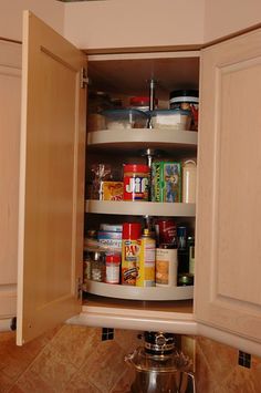 an open cabinet in a kitchen filled with food