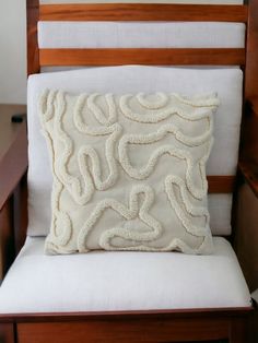 a white pillow sitting on top of a wooden chair