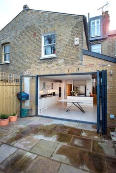 an open garage door in front of a brick building with a kitchen and living room