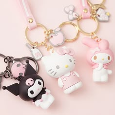 hello kitty keychains are laying next to each other on a pink surface,