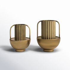 two golden vases sitting next to each other on a white surface, one is empty