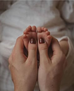 a person with brown nail polish holding their hands together