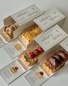 six different types of pastries in boxes on a white table with labels for them