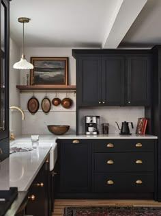 a kitchen with black cabinets and white counter tops, gold pulls on the cupboards