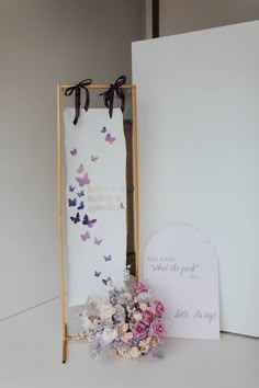 a bouquet of flowers sitting in front of a sign and greeting card with butterflies on it