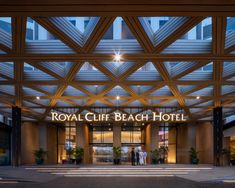 two people are standing in front of the royal cliff beach hotel entrance at night time