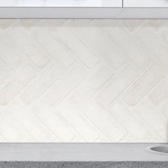 a white kitchen counter top next to a sink with a faucet on it