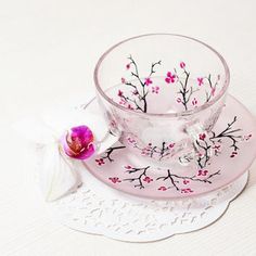 a glass cup and saucer with pink flowers on it