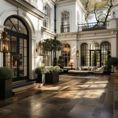 a large white building with lots of windows and plants in the courtyard area, surrounded by potted trees