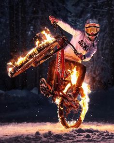 a person on a motorcycle doing tricks in the air with flames coming out of it