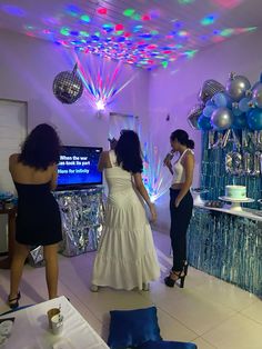 three women standing in a room with disco balls on the ceiling and balloons hanging from the ceiling