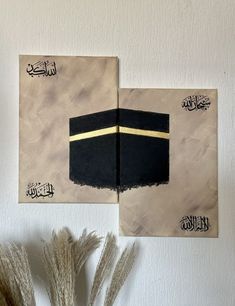 two paintings on the wall, one with a black hat and gold stripe in arabic writing