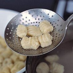 a metal strainer filled with cashews on top of a table