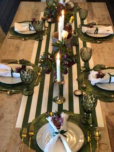 the table is set with plates, silverware and candles on top of green striped napkins