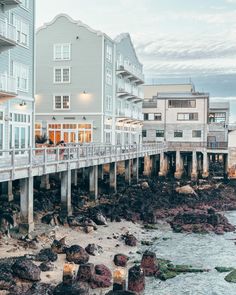 an oceanfront with several buildings and people walking on the walkway over to the water