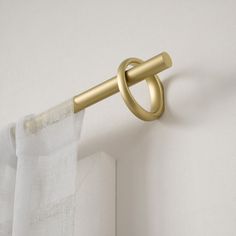 a curtain rod with a gold ring hanging from it's side on a white wall