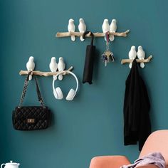 there are several birds hanging on the wall and two purses hang from hooks, while one bird is perched on a branch