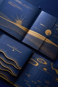 three blue and gold brochures are laying on top of each other in front of a dark background