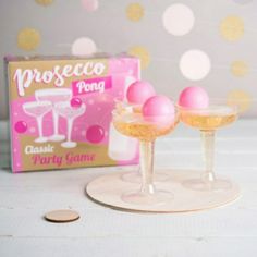 two glasses with pink balls in them sitting on a table