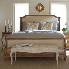 a bedroom with a bed, bench and pillows on top of the bedspread