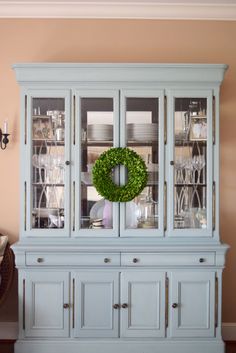 a white china cabinet with a wreath on top