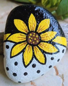 a painted rock with a yellow flower on it