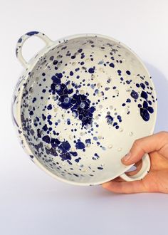 a hand holding a blue and white bowl with sprinkles on the bottom