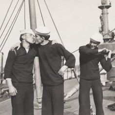 three men are kissing on the deck of a ship while another man is standing next to them