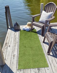 a green rug sitting on top of a wooden dock next to a chair and two chairs