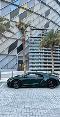 a green bugatti parked in front of a building with palm trees on the side