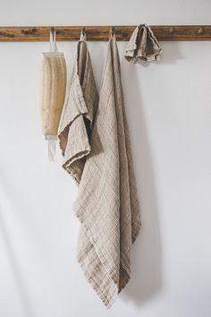 three towels hanging on a wooden rack in front of a white wall