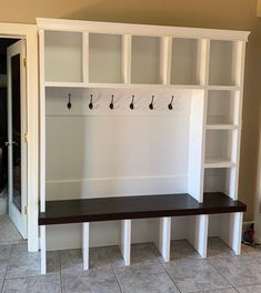 an empty room with several white shelves and hooks on the wall, along with tile flooring