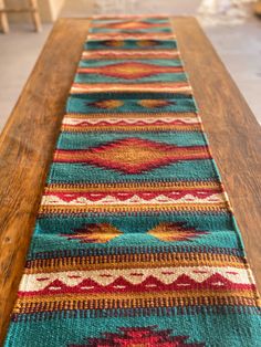 a long wooden table with colorful rugs on it