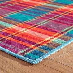 an orange, blue and green plaid rug on a wooden floor with a wood surface